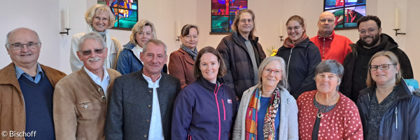 Die 14 Personen des erweiterten Kirchenvorstands fotografiert vor den bunten Fenstern der Dreifaltigkeitskirche.