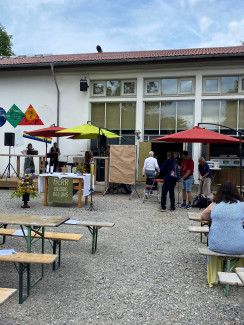 Viele Bierbänke und bunte Schirme auf dem Platz vor der Deckerhalle in Herzogsägmühle beim Dorffest Gottesdienst 2025