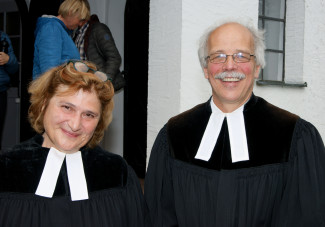 Prof. Johanna Haberer und Pfr. Jost Herrmann im Talar vor der Kirche