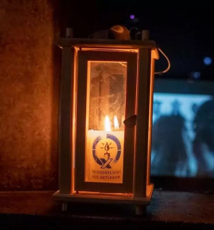 Das Friedenslicht aus Betlehem in einer Laterne, das Licht erhellt den dunklen Hintergrund