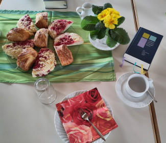 liebevoll gedeckter Tisch beim Gemeindenachmittag, mit Blumen, Gebäck und Gesangbuch