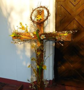 Ein Kreuz geschmückt mit blühenden Osterglocken und Tulpen