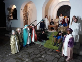 Schongauer Grundschüler verkleidet als Könige, Hirten, Engel, Maria und Josef vor dem Portal der Dreifaltigkeitskirche