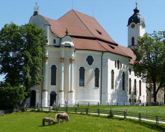 Die Wieskirche von der Südseite gesehen, im Vordergrund grasen Pferde auf der Koppel.