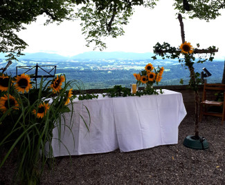 Sonnenblumen schmücken den Altar unter den Bäumen auf dem Hohen Peißenberg, mit Blick in die Alpen